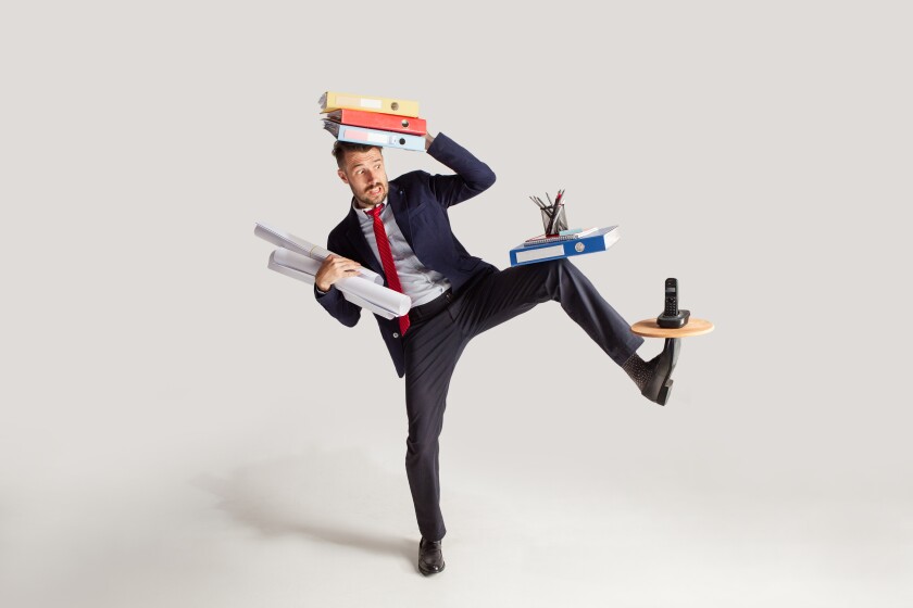 Young businessman in a suit juggling with office supplies in his office, isolated on white background