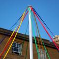 Colourful ribbons of maypole in front of cotswold stone building, Chipping Campden, Gloucestershire, England, United Kingdom, Europe
