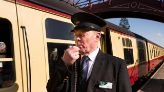 UK, England, Yorkshire, Goathland, North Yorkshire Moors Railway guard Peter Glenn, blowing whistle