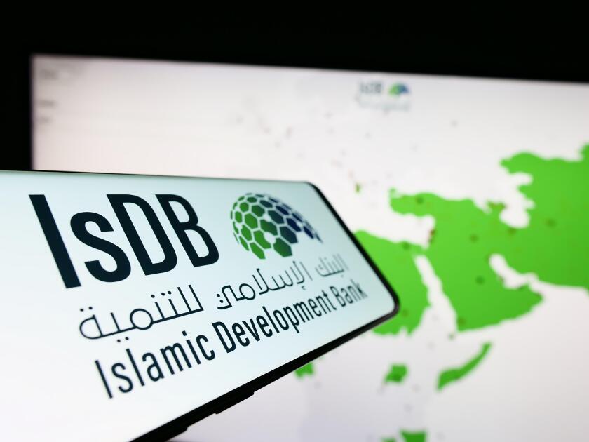 Cellphone with logo of Islamic Development Bank (IsDB) on screen in front of website. Focus on center-left of phone display.