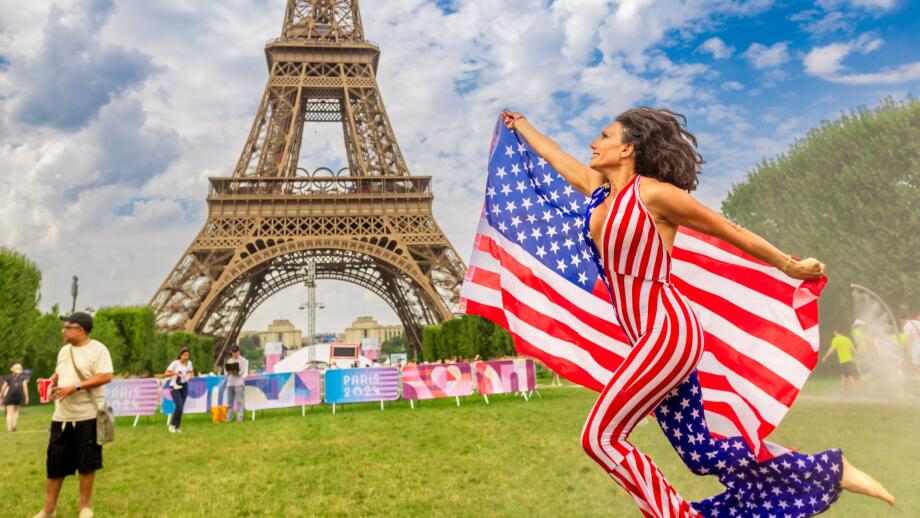 Patriotic American Woman jumping and cheering for Team USA and the Paris 2024 Olympics in front of the Eiffel Tower, Paris, France, Europe Copyright:
