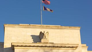 United States Federal Reserve headquarters in Washington DC, USA. Eccles Building with US National and Fed flags under clear sky in early morning.
