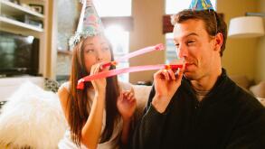 Young couple having fun with birthday hats.