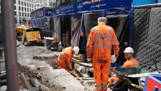 Thames Water worker and workmen work digging up road with buses on King William Street in the summer of 2019 City of London England UK  KATHY DEWITT