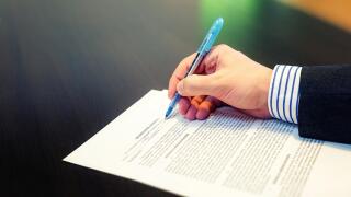Cropped closeup of a man hand filling in Non Disclosure Agreement (NDA). Reading and signing business concept