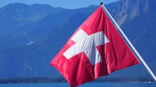 Red and white national flag on Lake Geneva, european Montreux city, canton Vaud in Switzerland, clear blue sky in 2017 warm sunny summer day on July.