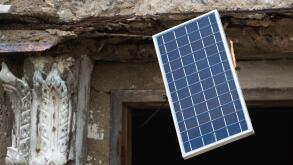 A solar panel hangs in the window of an old unmaintained building