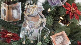 Christmas Tree with ten pound and twenty pound notes as decoration with a glass and gold reindeer in the foreground, expensive Christmas