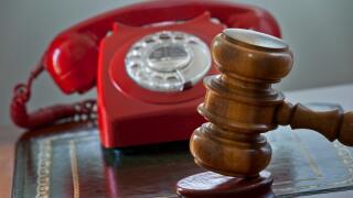 Traditional auction house concept with retro red telephone hot line bids and auctioneers gavel hammer on podium auction desk