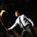 Image of brave man with burning stick in darkness