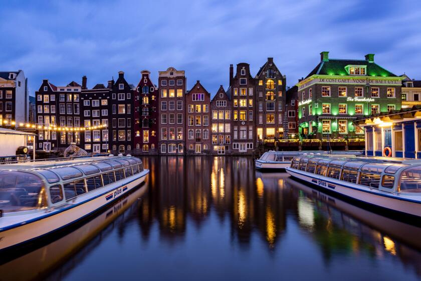 AMSTERDAM, THE NETHERLANDS - JANUARY 18, 2023: Cityscape of traditional Dutch houses during sunset at the Damrak canal in Amsterdam
