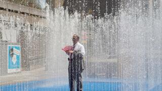 A man stands in a fountain on a sunny day on the South Bank in central London, Britain