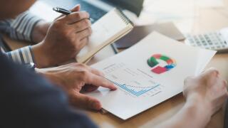 Businessman hand holding report document in office meeting room with business discussion and brainstorm atmosphere in blurry background.