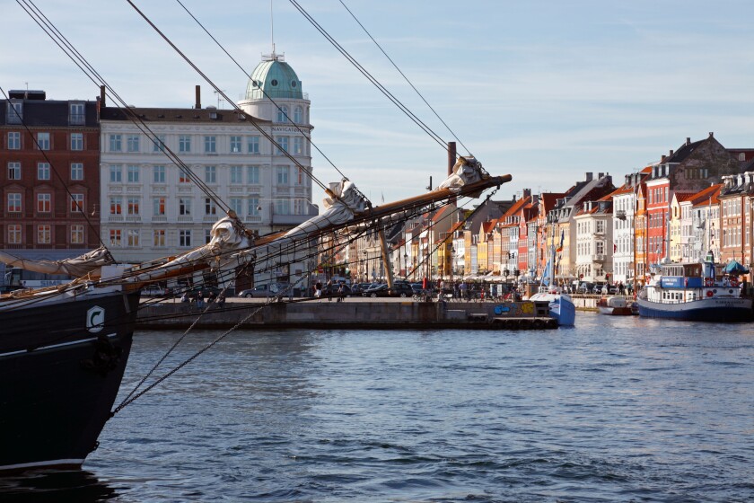 View at the Nyhavn canal across the harbour in the port of Copenhagen through the rig and  bowsprit of an old sailing vessel.