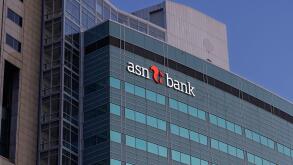 The contemporary glass and concrete facade of the ASN Bank building in Utrecht, with its distinct logo, stands prominently against a clear blue sky.