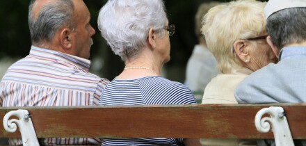 Elderly back sitting on a bench.