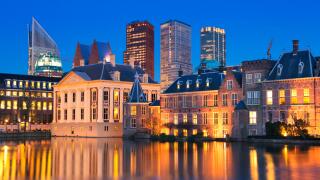 The Dutch Parliament buildings at the Binnenhof from across the Hofvijver pond in The Hague, The Netherlands at night.