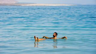 DEAD SEA; ISRAEL - 16 OCTOBER, 2014: A man floating in the salty water of the dead sea in Israel
