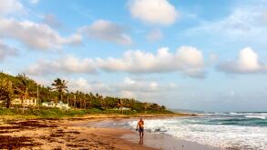 Man strolls the beach along the more rugged east coast of Barbados.