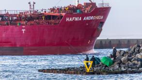 Tanker Hafnia Andromeda, enters the port of Ijmuiden, in North Holland, Netherlands, anglers at the pier,
