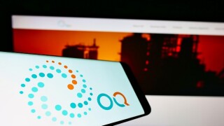 Smartphone with logo of Omani petroleum investment company OQ on screen in front of business website. Focus on center-right of phone display.