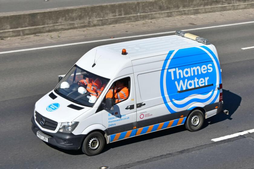 Hard hats & team of workers wear workmen's high visibility safety jackets traveling to work Thames Water logo on side of Mercedes van on UK motorway