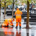 Two male employees of SGS in orange high-visibility clothing, making an inspection on the forecourt of King's Cross Station, London, UK