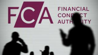 The FCA logo is seen on an LED screen in the background while a silhouetted person uses a smartphone in the foreground (Editorial use only)