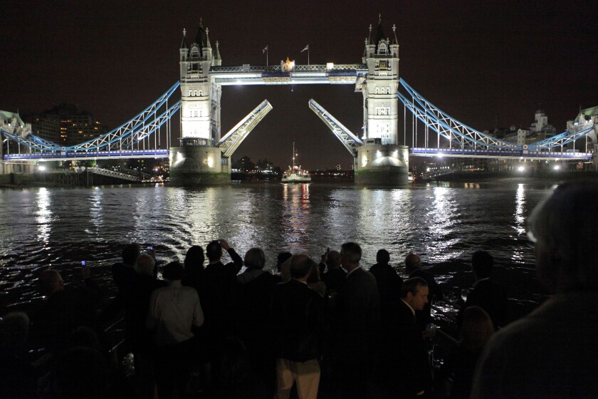 Nighttime photograph of Waverly Paddle Steamer going under Tower Bridge raised for the vessel watched by crowd, London, UK