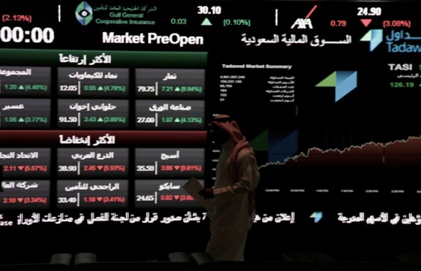A Saudi man walks at the Tadawul Saudi Stock Exchange, in Riyadh, Saudi Arabia, Monday, June 15, 2015.