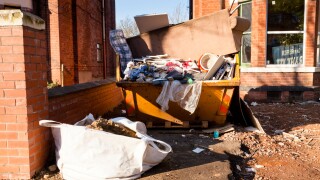 Home renovation. Full skip outside a house being renovated, England, UK