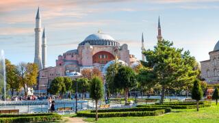 Tourists enjoy afternoon in Sultanahmet Square with the Hagia Sophia museum mosque in view in Istanbul, Turkey.