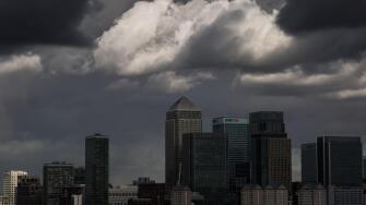 Dark storm clouds over Canary Wharf business park buildings in London