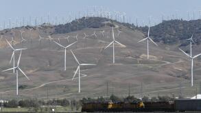 Tehachapi, CA. April 30, 2017. A cargo train passes beneath windmills in the Tehachapi Wind Resource Area, California's largest wind energy farm.