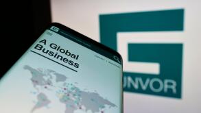 Cellphone with webpage of commodity trading company Gunvor Group Ltd on screen in front of business logo. Focus on center of phone display.