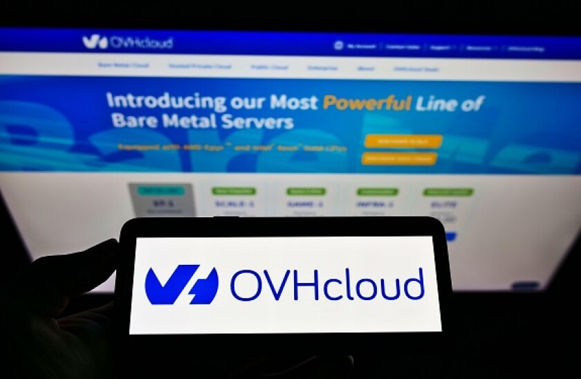 Person holding smartphone with logo of French cloud computing company OVH Groupe SAS on screen in front of website. Focus on phone display.