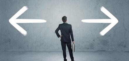 A businessman in doubt, having to shoose between two different choices indicated by arrows pointing in opposite direction concept