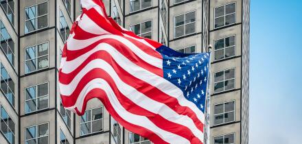 American flag in front of skyscraper.