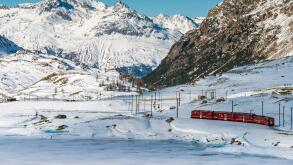 Bernina Express red train passing Lago Bianco in a scenic winter mountain landscape, Graubunden, Switzerland