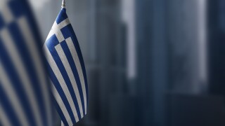 Small flags of Greece on a blurry background of the city