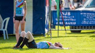 A man flat on his back while a lady is stood next to him after the 10k race at The Carvers sponsored Wolverhampton Marathon UK