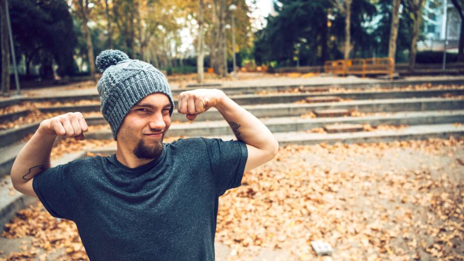 Man flexing muscles while standing in park during autumn