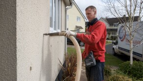 Man filling cavity wall with insulation, Devon