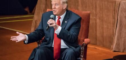 Donald Trump is seated answering questions at the Economic Club of New York.