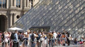 People wait line up near Pyramid at the Louvre Museum during a hot summer day with 30 degrees Celsius on August 25, 2022 in Paris,France.