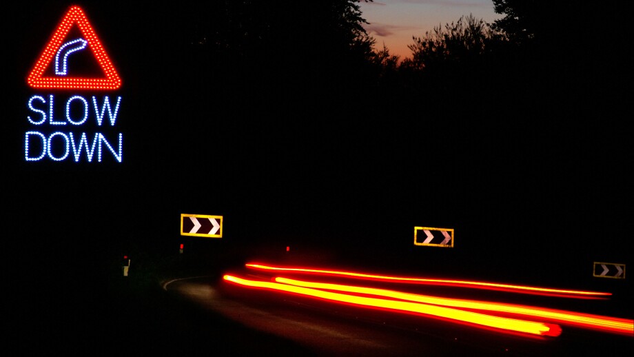 dangerous drive and speeding at night on the hairpin bend road. Slow DOWN sign