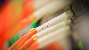 Fiber cables plugged into a high end router machine at a computer data center supporting cloud computing