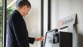 Young businessman buying cryptocurrency on ATM machine for buying and selling cryptocurrency.