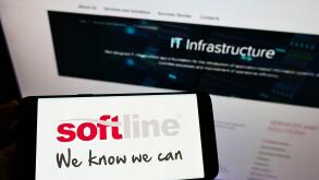 Person holding mobile phone with logo of global IT solutions provider Softline International on screen in front of web page. Focus on phone display.