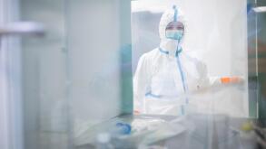 Lab technician wearing cleanroom overall at material sluice